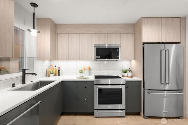 kitchen with a sink, backsplash, light brown cabinetry, and stainless steel appliances