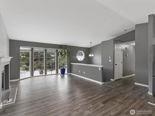 unfurnished living room with vaulted ceiling, a fireplace, dark wood finished floors, and baseboards