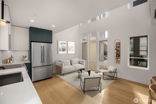 living room featuring light wood finished floors, baseboards, and recessed lighting