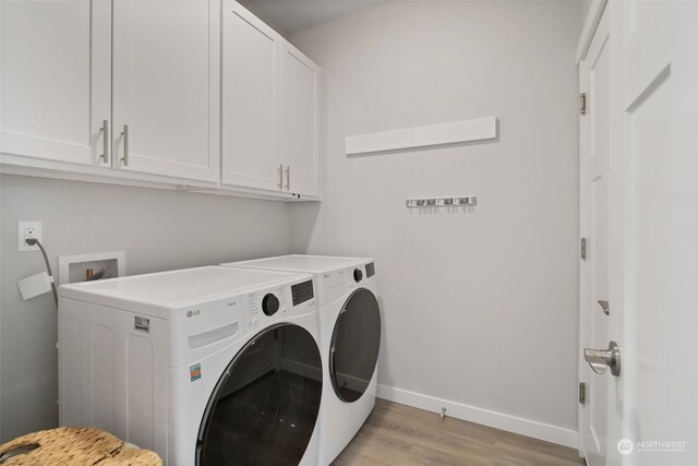 laundry room featuring washing machine and dryer, cabinets, and light hardwood / wood-style flooring