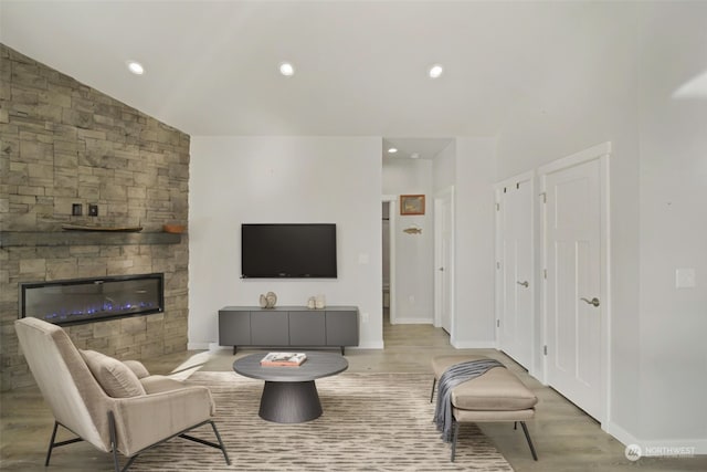 living room featuring a fireplace, light wood-type flooring, and vaulted ceiling