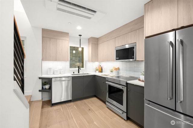 kitchen with stainless steel appliances, sink, decorative light fixtures, decorative backsplash, and light brown cabinetry