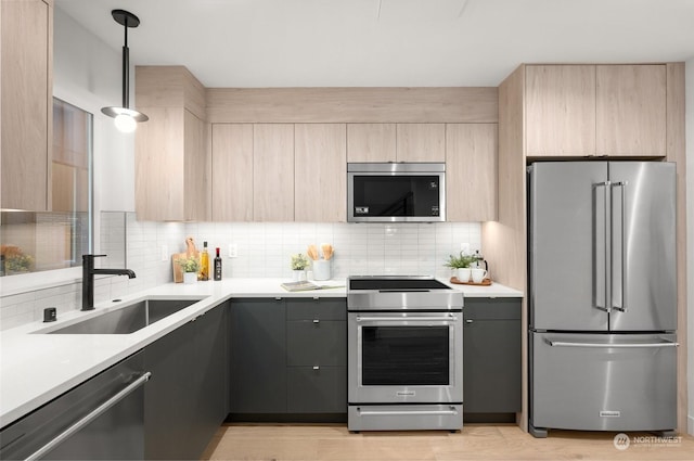 kitchen with sink, light brown cabinets, backsplash, hanging light fixtures, and appliances with stainless steel finishes