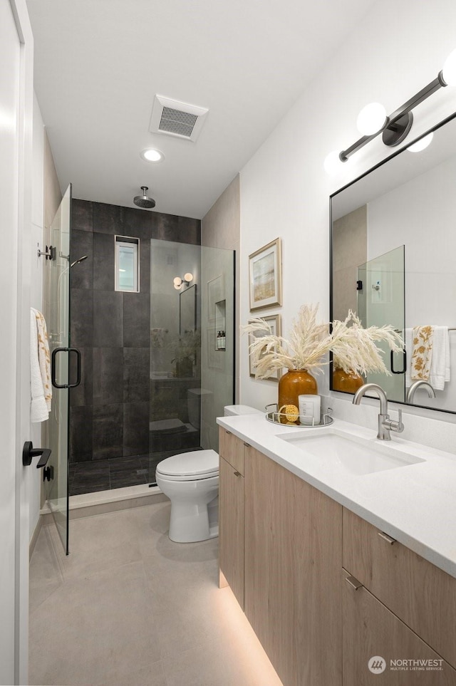 bathroom with vanity, a shower with shower door, and toilet