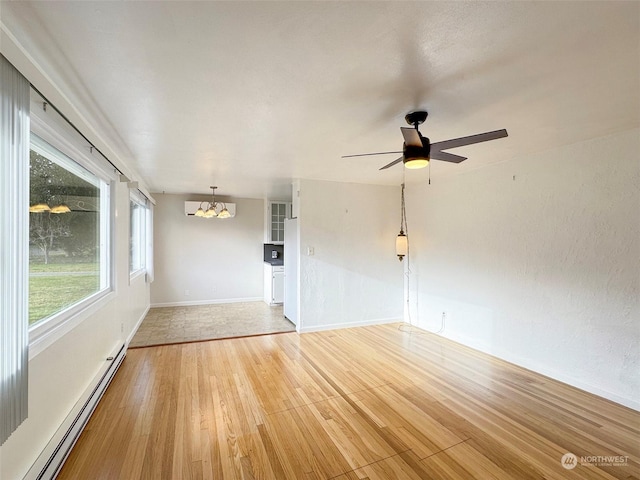 unfurnished room with hardwood / wood-style flooring, ceiling fan with notable chandelier, and a baseboard heating unit