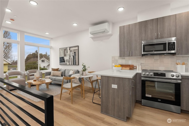 kitchen featuring dark brown cabinetry, kitchen peninsula, light hardwood / wood-style flooring, and appliances with stainless steel finishes