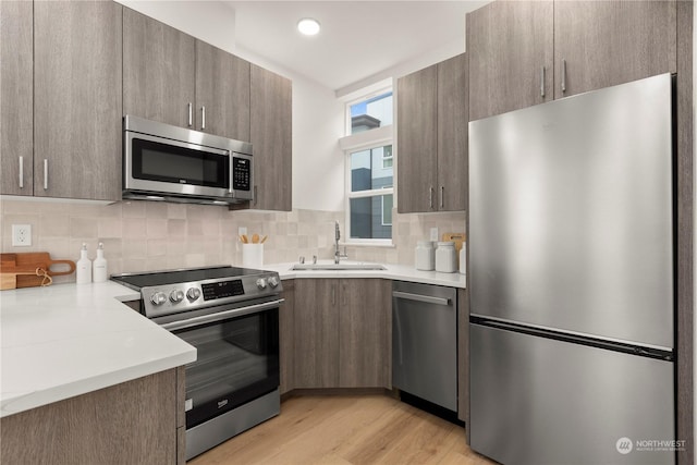 kitchen with decorative backsplash, sink, stainless steel appliances, and light wood-type flooring