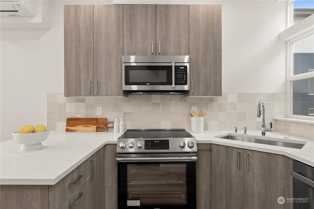 kitchen with light stone counters, sink, stainless steel appliances, and tasteful backsplash