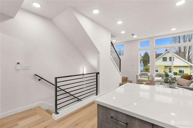 kitchen with light hardwood / wood-style floors, light stone counters, and dark brown cabinetry