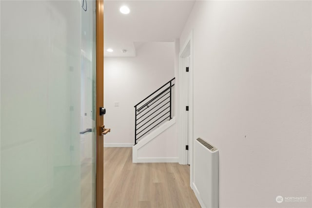 corridor featuring radiator heating unit and light hardwood / wood-style floors