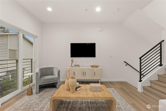 living room featuring light wood finished floors, baseboards, stairway, and recessed lighting