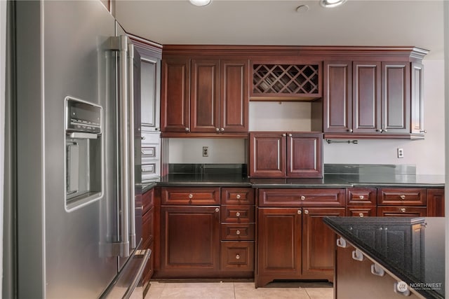 kitchen with light tile patterned floors, dark stone counters, and high end refrigerator