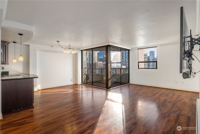 unfurnished living room with a wall of windows, dark hardwood / wood-style floors, and a notable chandelier