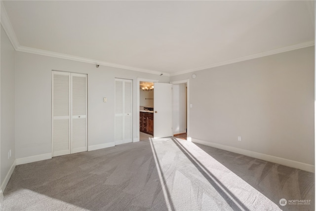 unfurnished bedroom featuring connected bathroom, crown molding, carpet, and a notable chandelier