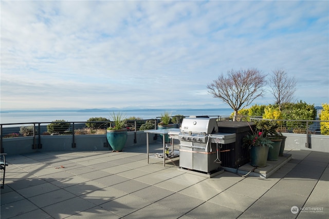 view of patio with grilling area and a water view