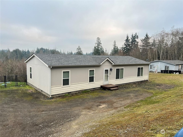 view of front of home with fence and roof with shingles