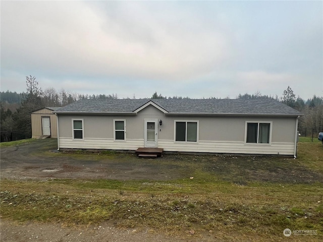 rear view of house featuring crawl space, an outdoor structure, and roof with shingles