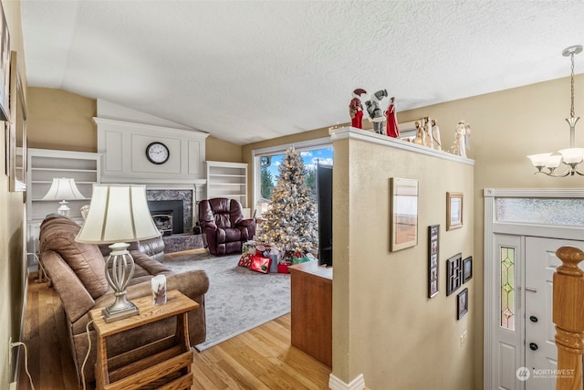 interior space with a fireplace, light hardwood / wood-style floors, vaulted ceiling, and a wealth of natural light