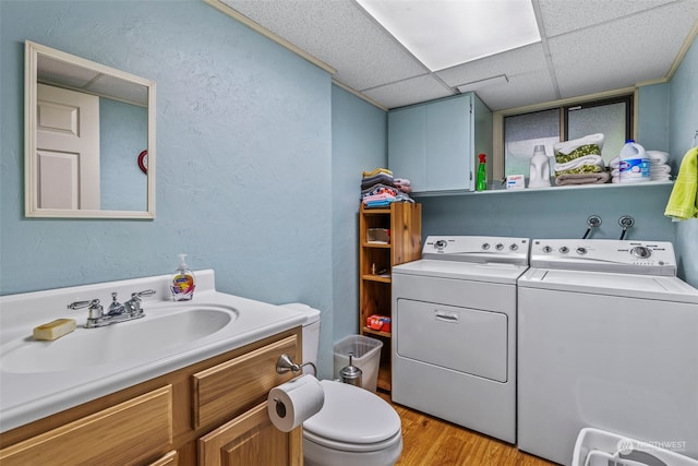 bathroom with a drop ceiling, vanity, separate washer and dryer, hardwood / wood-style floors, and toilet