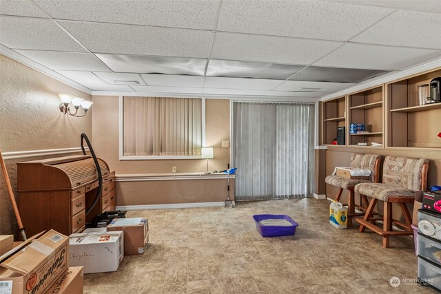 interior space with a drop ceiling and ornamental molding