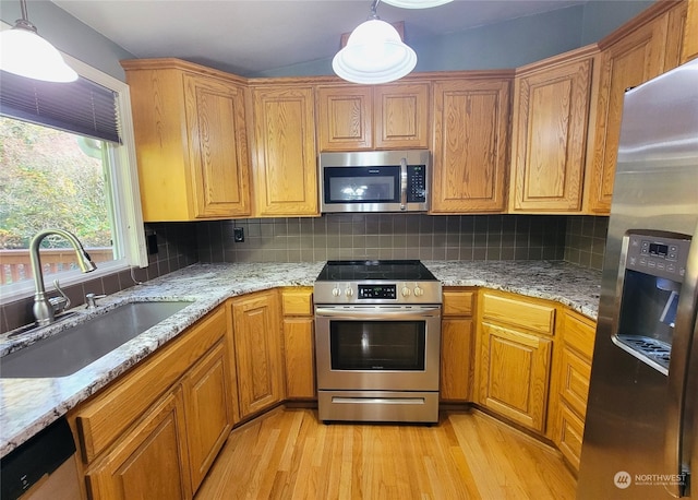 kitchen with pendant lighting, sink, decorative backsplash, light wood-type flooring, and appliances with stainless steel finishes