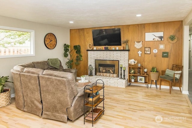 living room with wood walls, wood-type flooring, and a brick fireplace