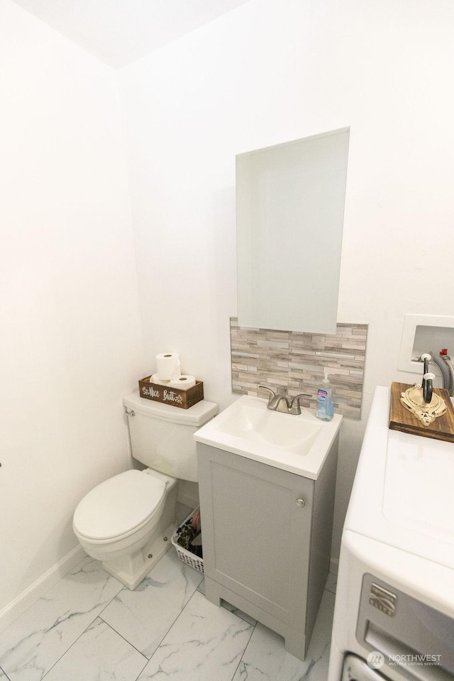 bathroom featuring toilet, vanity, and washer / dryer