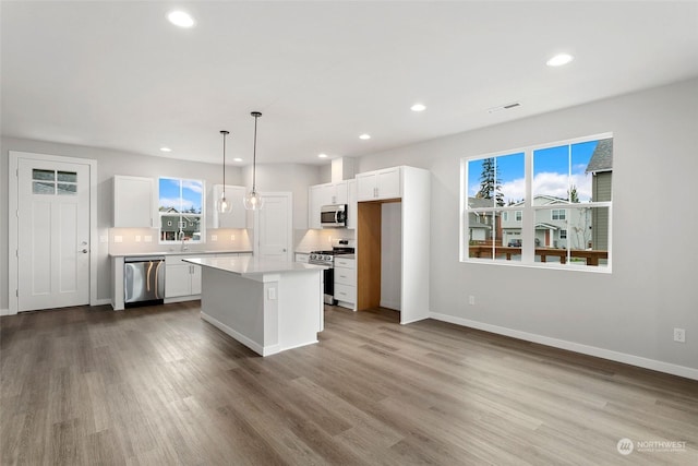 kitchen featuring pendant lighting, white cabinetry, a center island, and stainless steel appliances