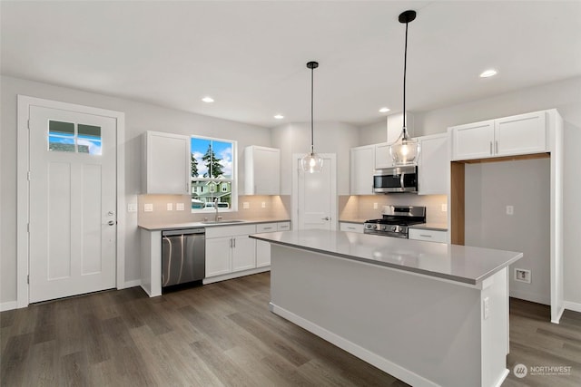 kitchen with decorative light fixtures, a kitchen island, sink, appliances with stainless steel finishes, and white cabinets