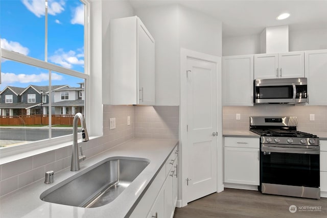 kitchen featuring tasteful backsplash, dark hardwood / wood-style floors, sink, white cabinetry, and appliances with stainless steel finishes