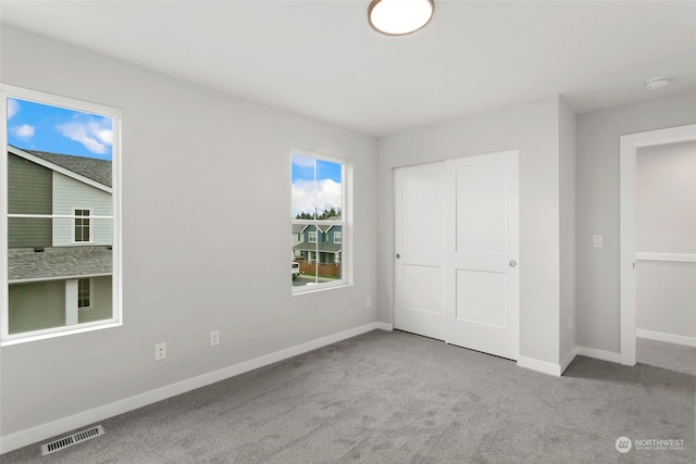 unfurnished bedroom featuring a closet and light colored carpet