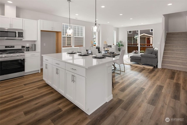 kitchen with decorative light fixtures, dark hardwood / wood-style floors, a center island, appliances with stainless steel finishes, and white cabinets