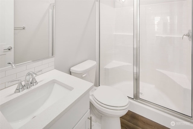 bathroom with tasteful backsplash, vanity, toilet, hardwood / wood-style floors, and a shower with door