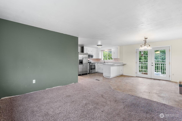 unfurnished living room with light colored carpet, sink, and an inviting chandelier