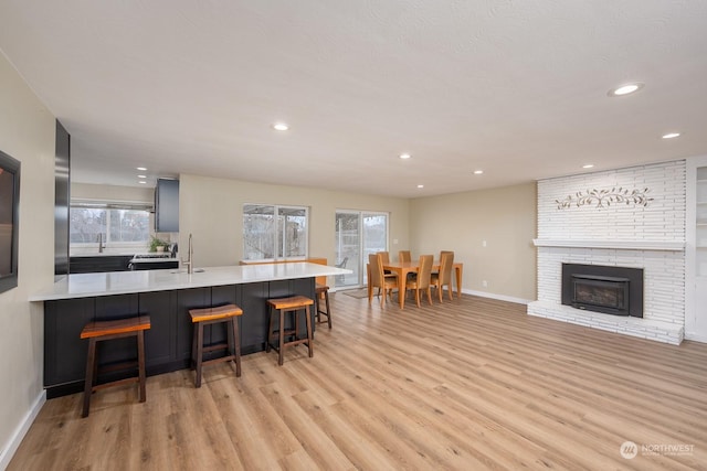 kitchen with kitchen peninsula, a kitchen bar, light hardwood / wood-style floors, and a fireplace