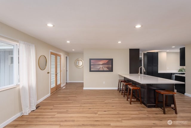 kitchen with a breakfast bar area, kitchen peninsula, sink, and light wood-type flooring