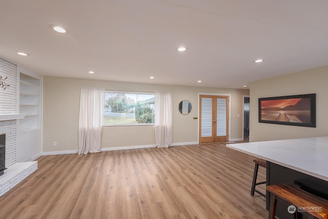 entryway featuring light hardwood / wood-style flooring, french doors, and a brick fireplace