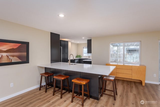 kitchen featuring light wood-type flooring, kitchen peninsula, sink, and a breakfast bar area