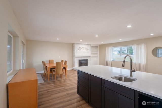 kitchen featuring a brick fireplace, sink, and light wood-type flooring