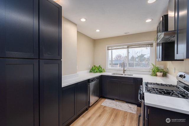 kitchen with light stone countertops, sink, ventilation hood, light hardwood / wood-style floors, and appliances with stainless steel finishes