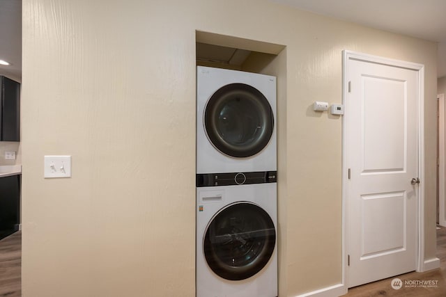 laundry area featuring hardwood / wood-style floors and stacked washer and clothes dryer