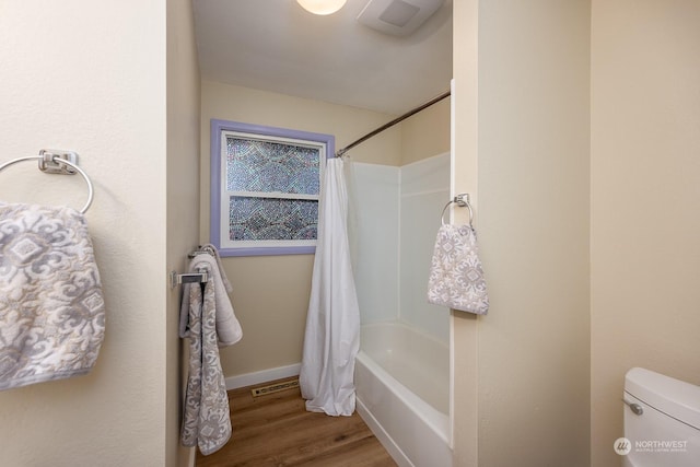 bathroom with hardwood / wood-style floors, shower / tub combo, and toilet