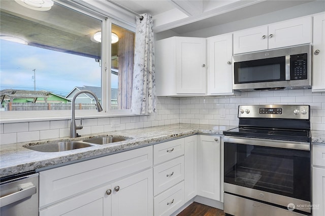 kitchen with backsplash, white cabinets, sink, light stone countertops, and appliances with stainless steel finishes