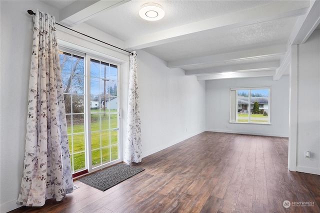 unfurnished room featuring beamed ceiling, dark wood-type flooring, and a textured ceiling