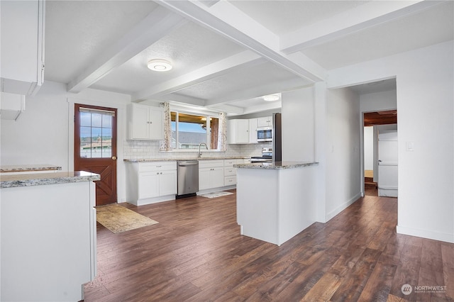 kitchen with beam ceiling, stainless steel appliances, white cabinetry, and dark wood-type flooring