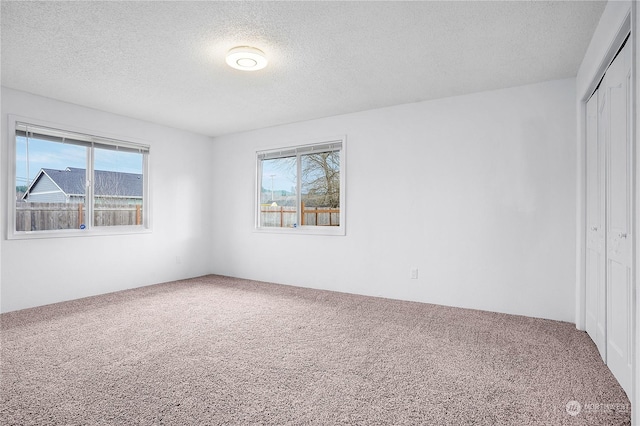 unfurnished bedroom featuring carpet flooring, a textured ceiling, and a closet