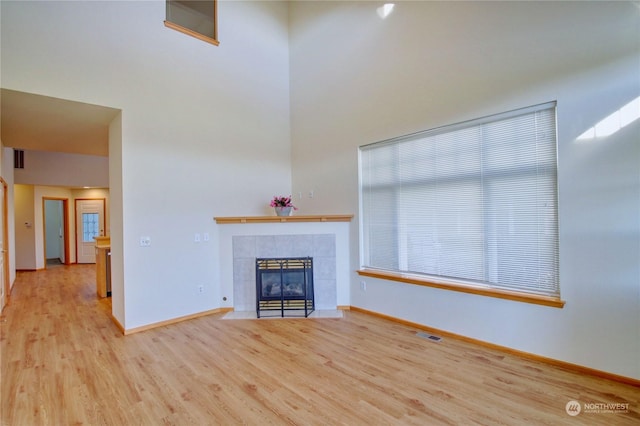 unfurnished living room featuring a tile fireplace and light hardwood / wood-style flooring