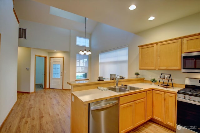 kitchen featuring kitchen peninsula, appliances with stainless steel finishes, light wood-type flooring, sink, and pendant lighting