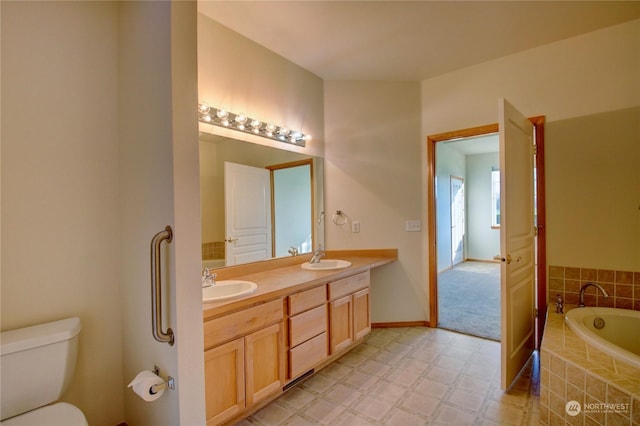 bathroom with vanity, toilet, and tiled bath