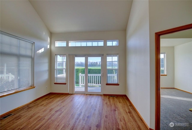 empty room featuring light hardwood / wood-style floors and high vaulted ceiling